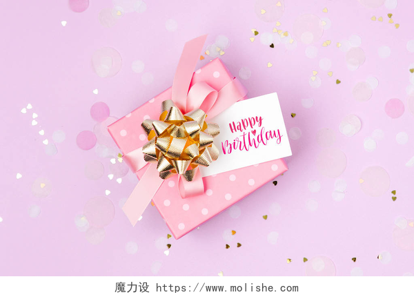 紫色装饰背景上的礼物盒子粉红色礼品盒与生日快乐标签在紫色装饰背景